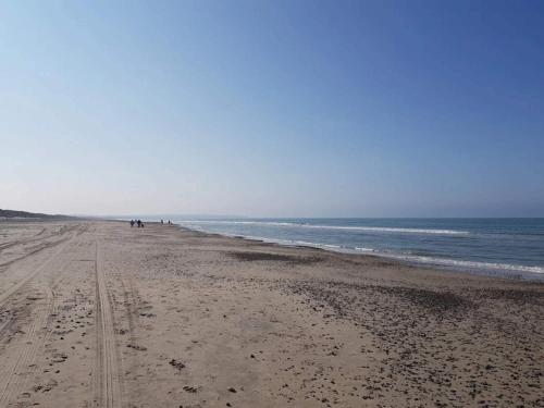 a beach with people walking on the sand and the ocean at 2 person holiday home in Brovst-By Traum in Brovst