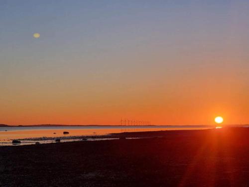 a sunset on a beach with the sun setting at 2 person holiday home in Brovst-By Traum in Brovst