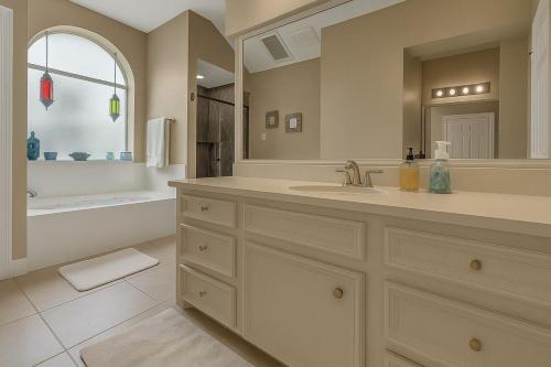 a bathroom with a sink and a tub and a mirror at Golfers' Paradise 3BR Single House with Private Pool & Golf Course View- Man Gated, Marina in Lake Conroe, Tennis courts & Gym Access in Montgomery