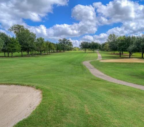 a view of a golf course with a dirt road at Golfers' Paradise 3BR Single House with Private Pool & Golf Course View- Man Gated, Marina in Lake Conroe, Tennis courts & Gym Access in Montgomery