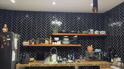 a kitchen with a black and white tiled wall at COP 30 BELEM - Casa de Luxo - 4 suítes in Marituba
