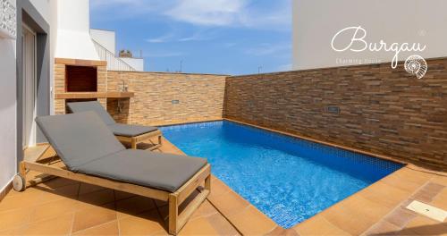 a patio with a chair and a swimming pool at Burgau Charming House Villa in Burgau