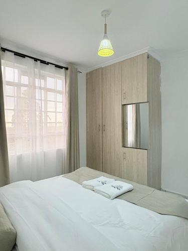 a bedroom with a large white bed and a window at Kevara by H&D Stays in Nanyuki