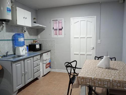 a kitchen with white cabinets and a table and a table and a door at Deptos Los Alerces in General Villegas