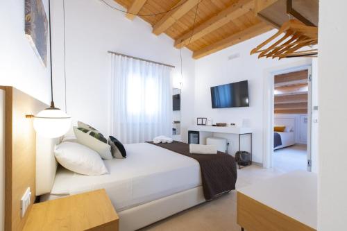 a white bedroom with a bed and a living room at Bed and Breakfast Nilu' in Castellammare del Golfo
