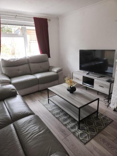 a living room with a leather couch and a flat screen tv at Beautiful two Bedroom house Entire house in Stevenage