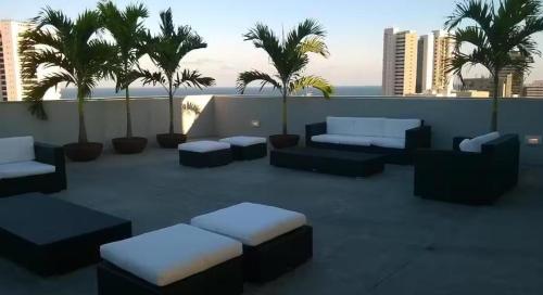 eine Terrasse mit Sofas und Palmen auf dem Dach in der Unterkunft Flat Premium Hotel Rãmada in Recife