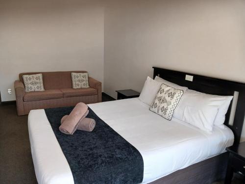 a bedroom with a large bed and a couch at Palm City Motor Inn in Napier