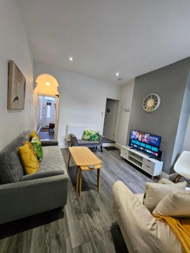 a living room with a couch and a tv at By the Joyous Stays - House with home comforts in Stoke on Trent