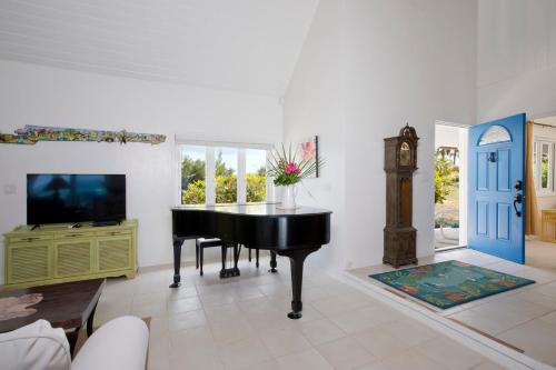 a living room with a piano and a television at Tourmaline home in Governorʼs Harbour