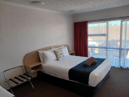 a bedroom with a bed and a large window at Palm City Motor Inn in Napier