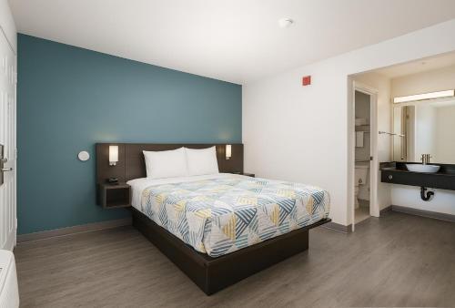 a bedroom with a bed with a blue wall at Motel 6-Westminster, CA - North in Westminster