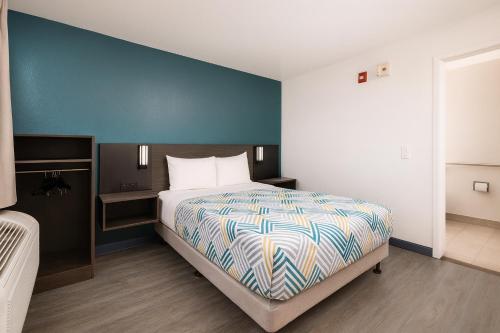 a bedroom with a bed and a blue wall at Motel 6-Westminster, CA - North in Westminster