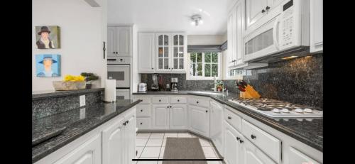 a kitchen with white cabinets and black counter tops at Chic Venice Beach Bungalow Steps from the Canals & Beach in Los Angeles