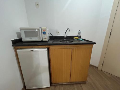 a kitchen with a microwave and a sink at Hotel Mercu Privi Moema Ibirapuera com ar e piscina 1810 in Sao Paulo
