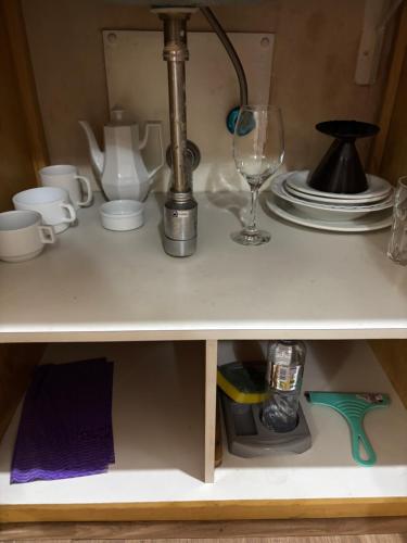 a shelf with a table with dishes and a wine glass at Hotel Mercu Privi Moema Ibirapuera com ar e piscina 1810 in Sao Paulo