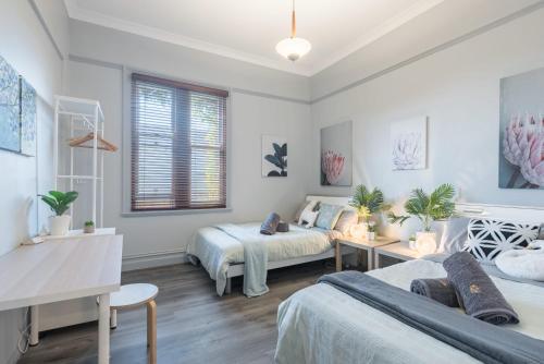 a bedroom with two beds and a table at Big Quadruple Room - Nearby Station and Park - Close to Chinatown - Shared Bathroom in Sydney