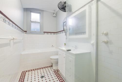 a white bathroom with a toilet and a shower at Big Quadruple Room - Nearby Station and Park - Close to Chinatown - Shared Bathroom in Sydney