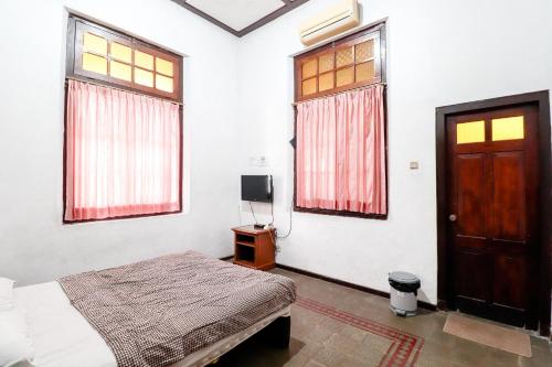a bedroom with a bed and a door and windows at Hotel Limaran 1 in Yogyakarta