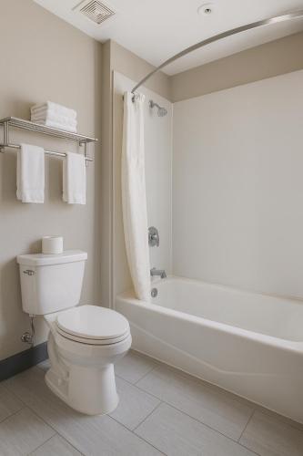 a white bathroom with a toilet and a bath tub at Motel 6-Westminster, CA - North in Westminster