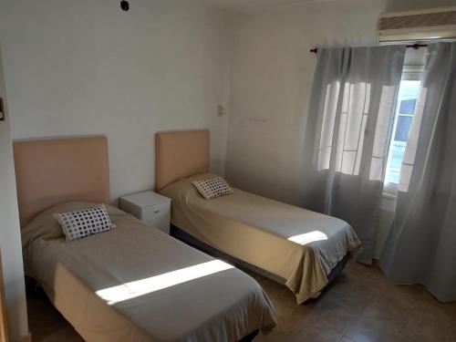 two beds in a room with a window at Alquiler Temporario Casa Cervantes in Paraná