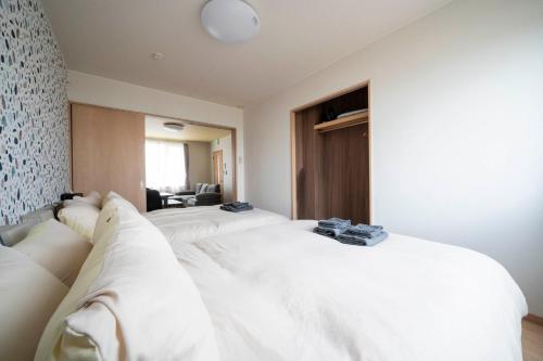 a hotel room with two white beds in it at Lambrusco in Kami-furano
