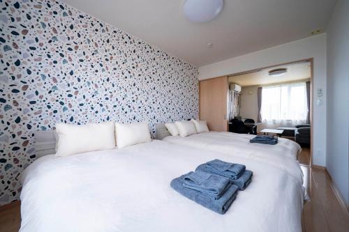 a bedroom with a white bed with towels on it at Lambrusco in Kami-furano