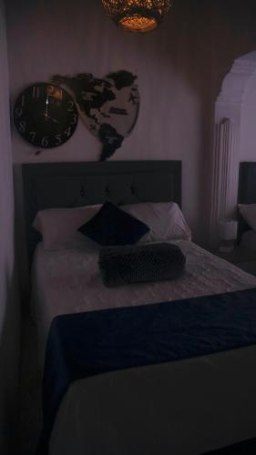 a clock on the wall above a bed with pillows at Casa Boutique La Corona Medellin in Envigado