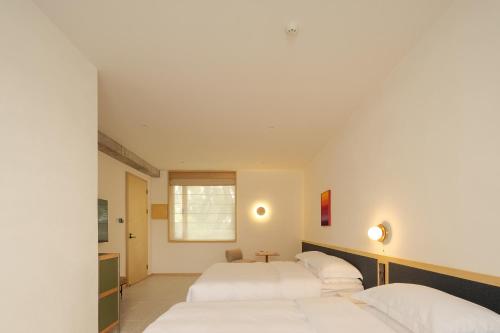 two beds in a room with white walls at songzhiyu3平江路 in Suzhou