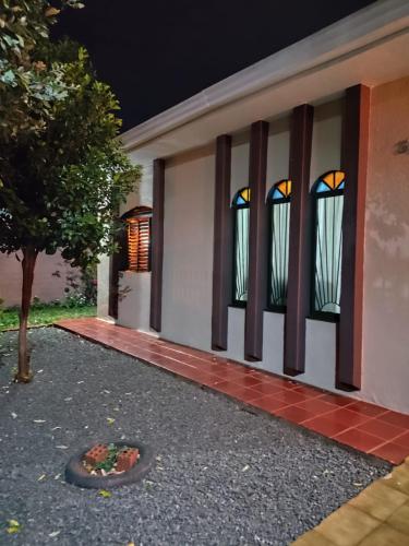 a house with two windows and a flower bed in front at Quartos em casa compartilhada na Cidade Canção Maringa in Maringá