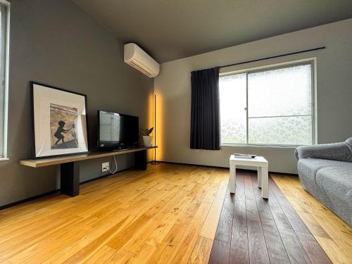 an empty living room with a couch and a television at Rino-Haku 01 in Anan