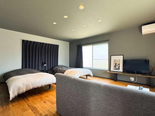 a living room with two beds and a tv at Rino-Haku 01 in Anan