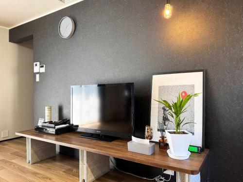 a television on a wooden table with a clock on a wall at Rino-Haku 01 in Anan