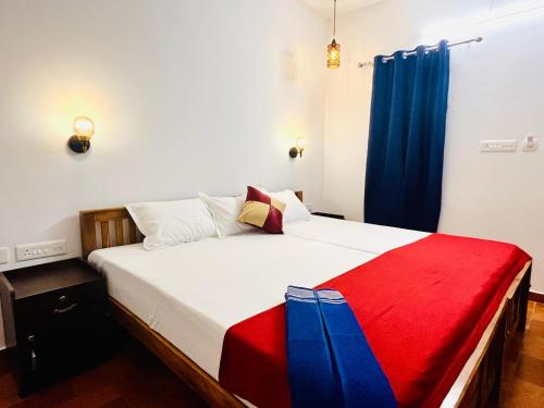 a bedroom with a bed with a red and blue blanket at Marari Anandu Beach Villa in Mararikulam