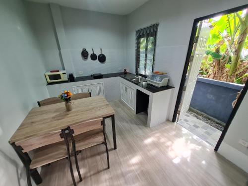 a kitchen with a wooden table and a wooden floor at D&A Paradise Villas in Koh Samui