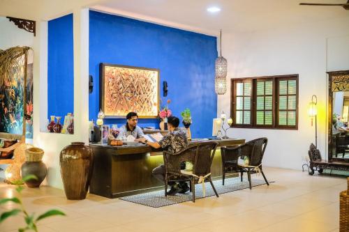 two people sitting at a table in a room with a blue wall at Tropical Langkawi in Pantai Cenang