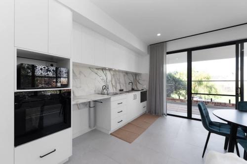 a white kitchen with a table and a dining room at Mangini Apartments in Perth