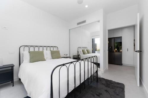 a bedroom with a large bed with white sheets and green pillows at Mangini Apartments - Unit 1 in Perth