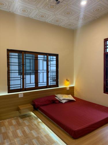 a bedroom with a large red bed with windows at Homestay Ly Angela in Ấp Mỹ Hải
