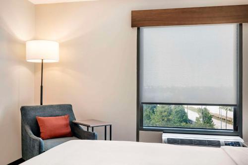 a hotel room with a bed and a chair and a window at Cambria Hotel Orlando near Universal Theme Parks in Orlando