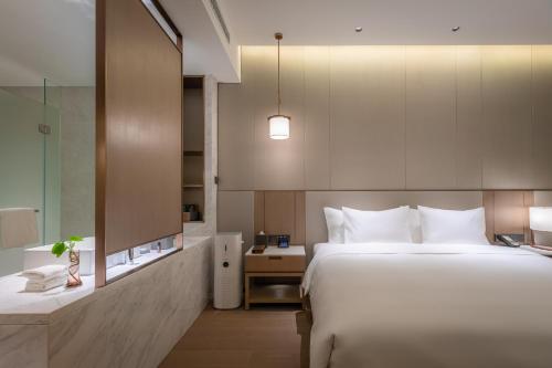 a bedroom with a large white bed and a bathroom at NARADA Fuzhou Fujian Hotel in Fuzhou