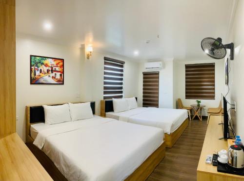 two beds in a room with white walls and wooden floors at Jademay Airport Hotel in Sóc Sơn