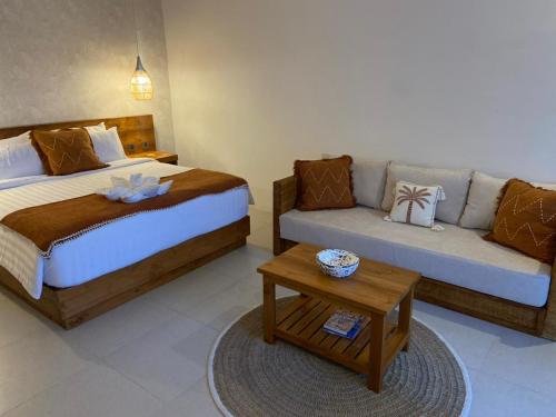 a bedroom with two beds and a couch and a table at Santai Suites Nusa Dua in Nusa Dua