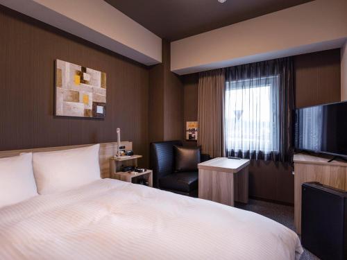 a hotel room with a bed and a chair at Hotel Route-Inn Kitamatsudo Ekimae in Matsudo