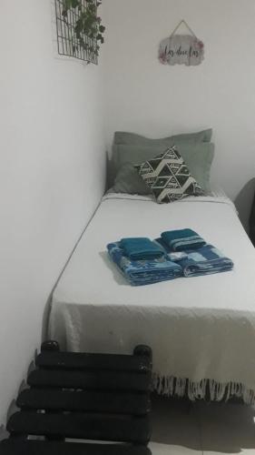 a white bed with blue sheets and pillows on it at Studio na Urca in Rio de Janeiro