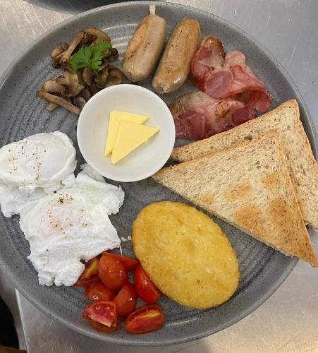 a plate of breakfast food with eggs sausage and bread at Santai Suites Nusa Dua in Nusa Dua