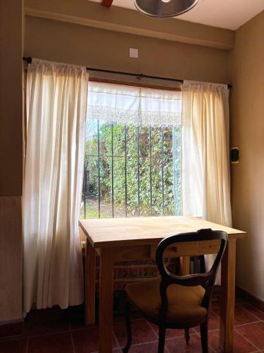 a table and a chair in front of a window at Encantadora y espaciosa casa a dos cuadras de Laguna Chascomús in Chascomús