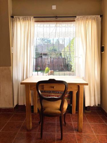 a wooden table with a chair in front of a window at Encantadora y espaciosa casa a dos cuadras de Laguna Chascomús in Chascomús