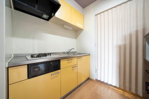 a kitchen with yellow cabinets and a sink and a window at Lambent in Kami-furano
