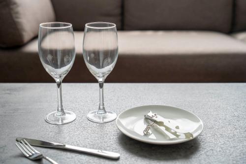 two wine glasses and a plate on a table at Lambent in Kami-furano